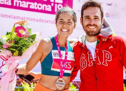 Smiling marathon winner with medal and flowers celebrates with friend.